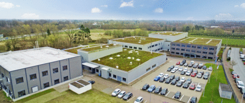 Luftaufnahme des COG Firmenstandorts in Pinneberg mit mehreren Industriegebäuden, begrünten Flachdächern und Parkplatz